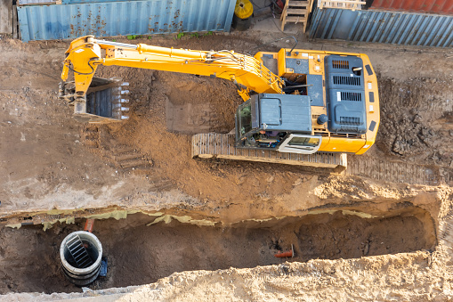 excavator working near a man hole on a construction site